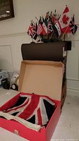 Three folded full size Union Jack flags in a box with some other items around