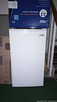 Front view of white Arctic King mini fridge with box labeled 3.3 cu.ft capacity on top.