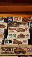 Photo showing stacked boxes of six 1:35 scale model kits including tanks and jeep from Tamiya and Italeri.