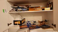 Shelf showing small plastic model airplanes, a pull-back metal plane, and model building magazines
