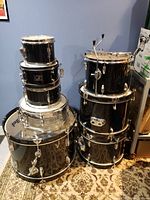 Full front view of stacked drums showing bass drum at bottom, silver snare and black rack toms