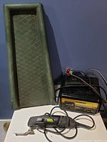 Green downspout ramp, Stanley multi-tool, and black battery charger with attached cables and clamps.