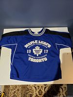 Front view of blue and black Toronto Maple Leafs kids hockey jersey.