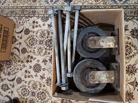 Box containing two large caster wheels with thick metal brackets and five large bolts