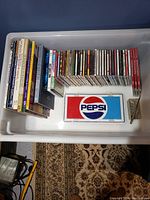 Top-down view of media bin showing books, CDs, DVDs and Pepsi sign arranged in rows