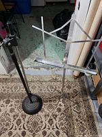 Full view of the black microphone stand with its round weighted base and the foldable silver metal music stand with adjustable arms.