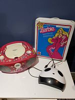 Barbie Fashion Doll Case standing upright next to pink CD player boombox and small panda speaker on table.