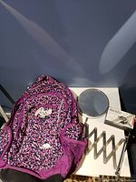 Backpack and extendable wall mirror on white table surface