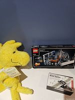 Photo of LEGO Technic Music Box Kit in box next to Woodstock plush