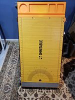 Top view of the Omni work table showing the wood-patterned surface with printed protractor, orange molded organizer with cup holder and slots.