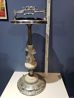 Front view of the retro ashtray stand showing the metal tray and ornate handle with marble pedestal base and floral carving details.