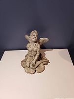 Side view of the stone fairy statue on rocks, showing detailed features and surface texture.