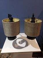 Pair of table lamps with beige textured fabric shades and black metal bases, showing front view.