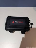 Closed black hard plastic carrying case with TruTorch logo and 'Tactical Flashlight' text in red and gray.