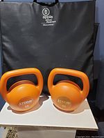 Photo of two orange 15-lb Tone Fitness kettlebells showing front and side