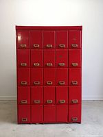 Front view of red painted oak apothecary cabinet with 25 drawers and cast iron recessed pulls
