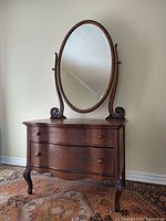 Full view of the antique tiger oak dresser with oval mirror attached, showing the wave front drawers and curved legs.
