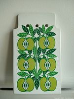 Front view of the ceramic trivet showing green stylized apple halves and leaves design.