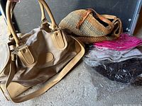 Photo displaying a tan leather-like duffel bag, woven handbag, and packaged slouchy hats