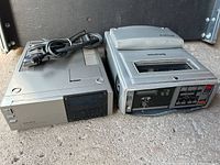 Sony Betamax player and tuner timer unit side by side on a concrete surface.