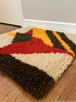 Close-up angled view showing the thick high pile texture and the bold geometric color blocks of the rug.