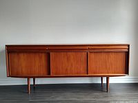 Front view of teak credenza showing sliding doors and tapered legs