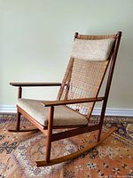 Front left three-quarter view showing overall form, teak frame, cane back, and upholstered seat.