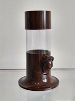 Full view of the Termotex dispenser with clear acrylic cylinder and brown base, showing the dispensing lever.