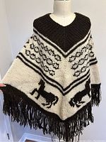 Full front view of the vintage wool knit cape showing horse motif and fringe detail.