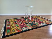 Rug laid on wood floor with chair for scale, showing full dimensions and pattern