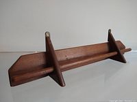 Side angle view of the vintage walnut wooden wall mount bar showing the rod and angled supports.