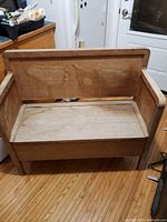 Front view of the antique wooden bench showing the seat, backrest, and armrests made from natural wood.