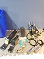 Photo showing two hitch extensions, pedal, clamps with blue grips, metal hook, and wiring bundle