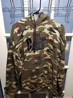 Front view of camouflage hoodie with CAT logo in black on chest, showing hood and kangaroo pocket