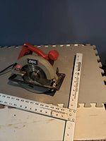 Skil circular saw showing the blade and red handle on foam mat background.