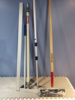 Photo showing drywall tools against a wall including drywall square, drywall hawk, taping knives, and corner trowel.