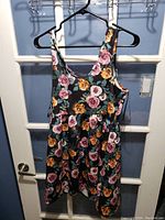 Front view of new sleeveless floral dress hanging on black hanger