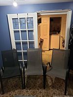 Two black patio chairs positioned indoors, showing full view of both chairs.