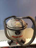 Front view of gray and black Shop-Vac wet/dry vacuum cleaner with hose wrapped around top, showing brand label and wheels.