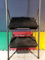 Front view of two-step step ladder showing black textured steps with embossed Cosco brand and aluminum frame