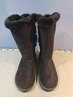 Front view of black suede UGG boots showing fur lining at the top.