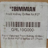 Close-up photo of a label on one box showing brand Bimmian, indicating front kidney grilles for BMW F07 model with part number GRL10G000, paint matched front kidney grilles for BMW F07 5 Series GT.