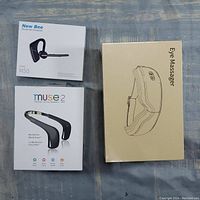 Three sealed boxed items laid flat: Electric Eye Massager, Muse 2 Brain Sensing Headband, and New Bee M50 Bluetooth Headset.