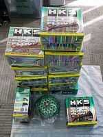 Stack of 13 HKS filter boxes with one loose green filter element in front