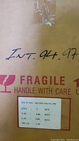 Cardboard box with handwritten INT 94 97 and fragile label, shows packaging details.