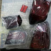 Four red smoke LED rear lens covers in packaging on bubble wrap, including smaller signal lenses.