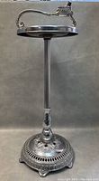 Full view of the chrome floor smoking stand with circular ashtray and ornate base.