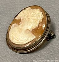 Close-up front and side angled view of the 1-inch Art Deco shell cameo brooch pendant showing the carved female profile and the silver frame. Visible crack on the shell.