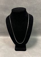 The full-length view of the sterling silver chain on a black display bust showing its 22-inch length and smooth flat chain design.
