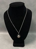 Sterling silver necklace displayed on a black bust, showing the circular pendant with a dome center.